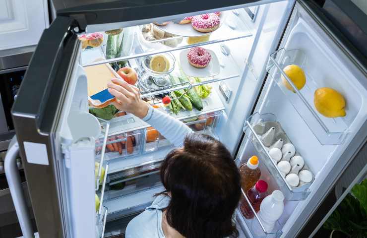 Una donna raccoglie del cibo dal frigo