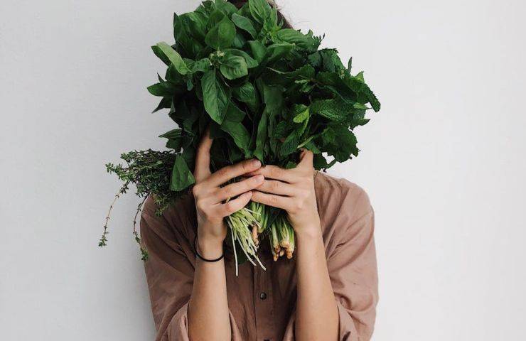 Una donna regge delle verdure tra le mani