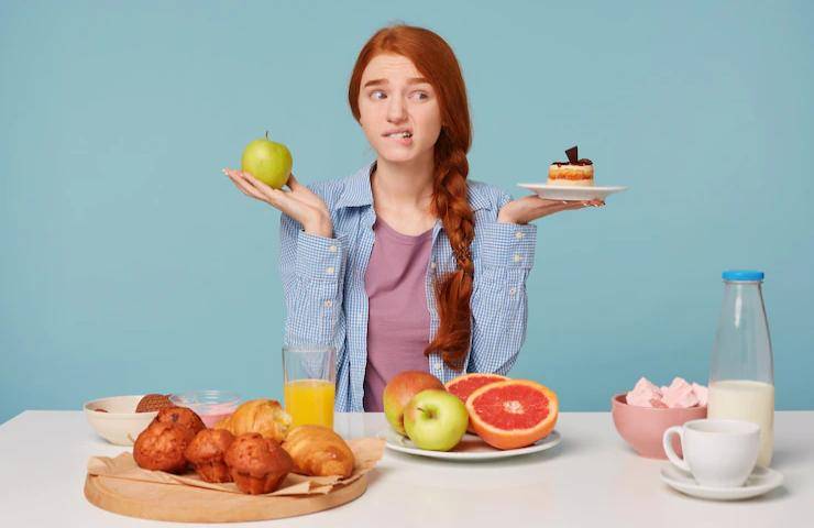 Una ragazza con davanti a sé diversi tipi di cibo