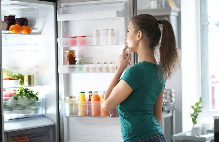 Una ragazza guarda cosa c'è in frigo