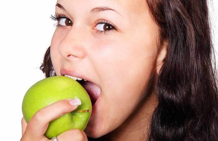 Una ragazza mangia una mela verde