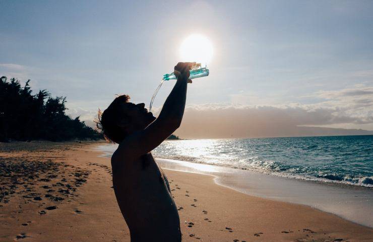 Un uomo beve acqua da una bottiglietta