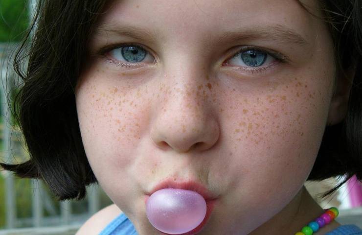 Una bambina fa un palloncino con una gomma da masticare