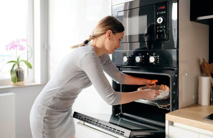 Una donna estrae una pietanza dal forno
