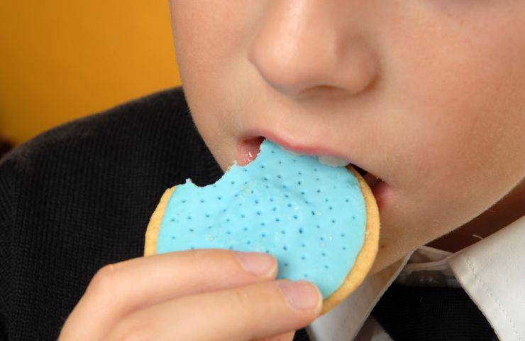 Un bambino mangia uno snack grasso