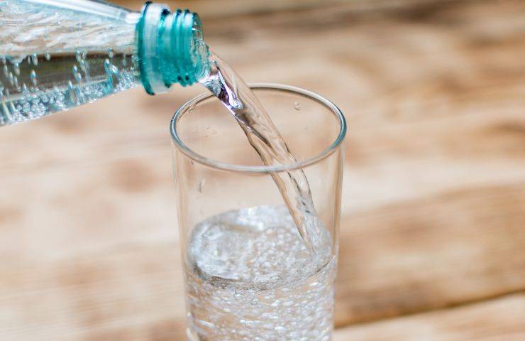 Un bicchiere di vetro mentre viene riempito di acqua frizzante