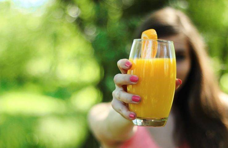 Una donna pronta a bere del succo di arancia