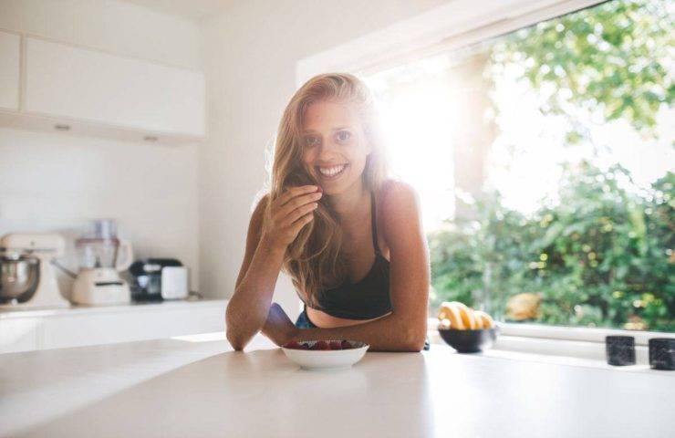 Una donna sorride mentre mangia un piatto sano