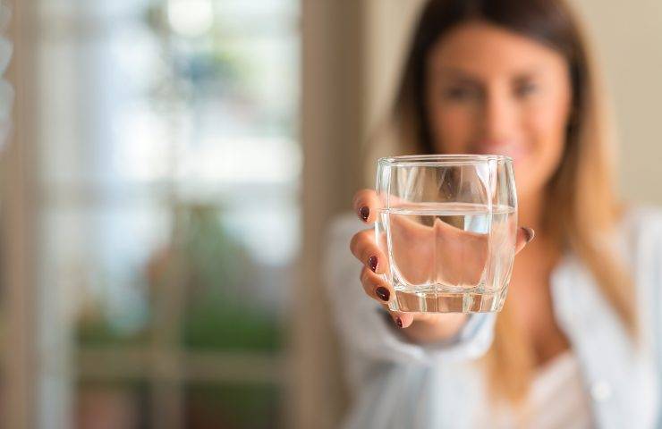 Una donna regge un bicchiere d'acqua