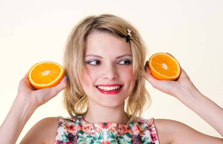 Una donna tiene due metà di arance