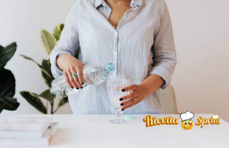 Una donna versa dell'acqua in un bicchiere
