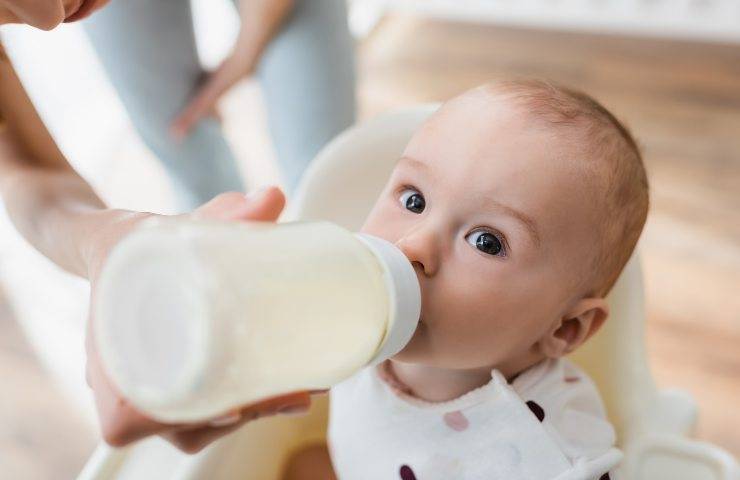 A baby drinks milk from a bottle