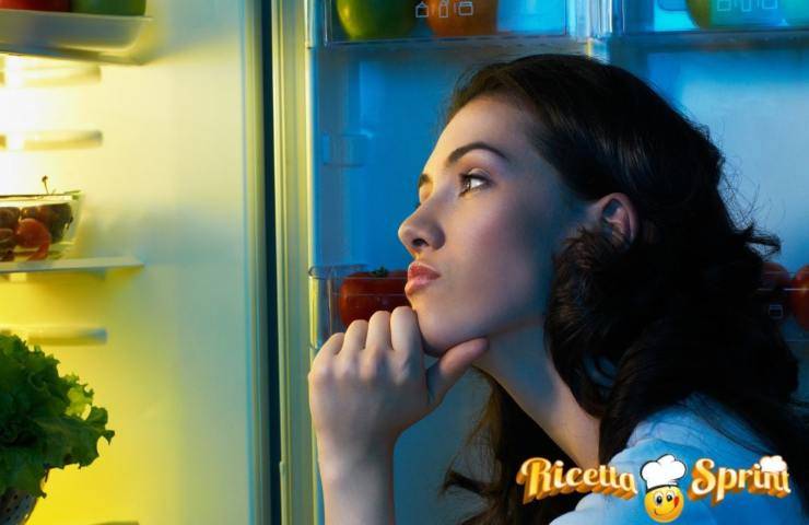 Una donna osserva il cibo in frigo