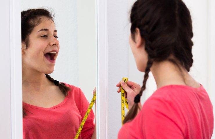 Una ragazza mentre si ammira allo specchio (Foto Canva - Ricettasprint.it 18122022)
