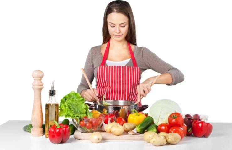Una donna mentre cucine diversi ortaggi