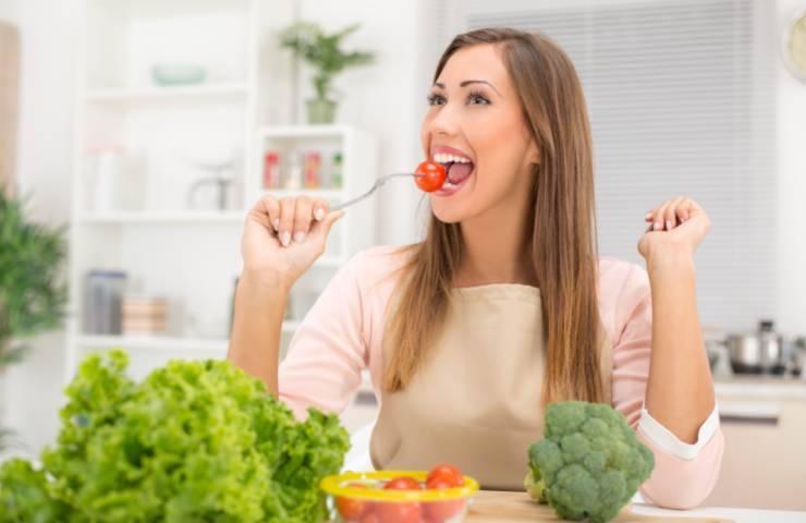 Una donna mentre mangia delle verdure