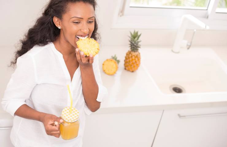 Una donna mentre mangia un ananas