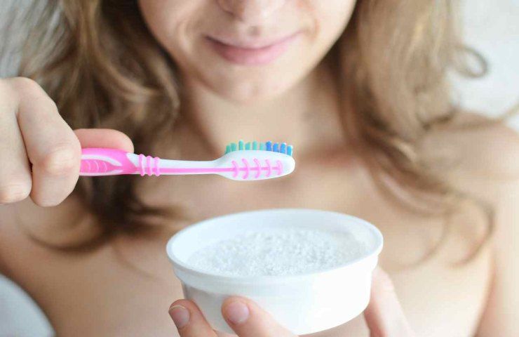 Una donna usa il bicarbonato per lavare i denti