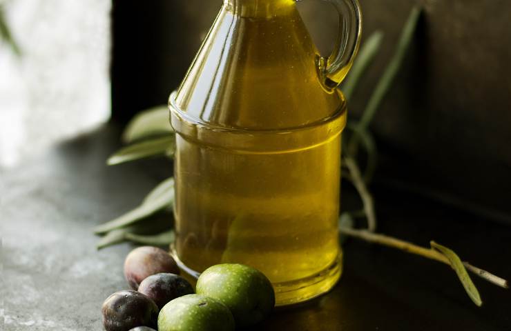 Una bottiglia trasparente ripiena d'olio extravergine d'oliva (Foto Canva Ricettasprint.it 26032023)