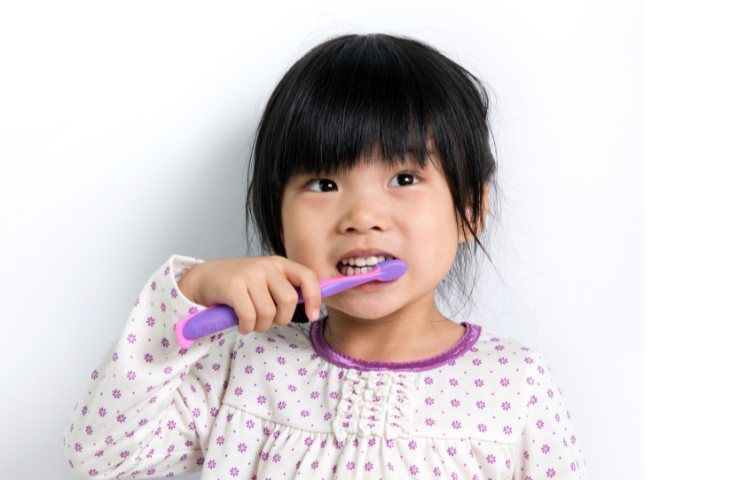 Una bambina che lava i denti