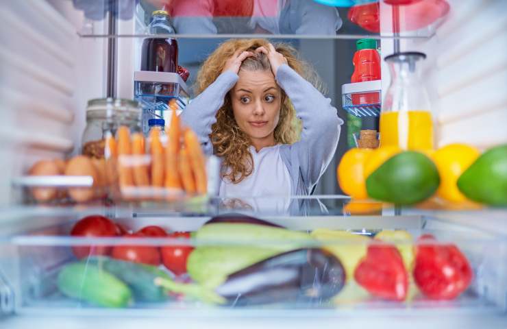 Una donna osserva l'interno del suo frigo di casa