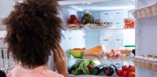 Una donna davanti al frigo pieno aperto
