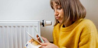 Donna conta i soldi vicino ad un termosifone
