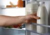 Uomo prende bottiglie di latte in frigo