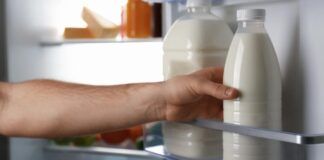Uomo prende bottiglie di latte in frigo