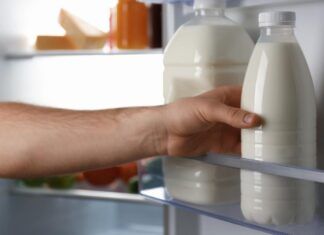 Uomo prende bottiglie di latte in frigo