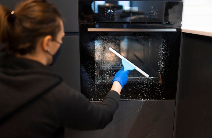 Persona che pulisce il vetro del forno