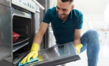 Uomo pulisce il vetro del forno