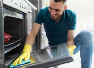 Uomo pulisce il vetro del forno