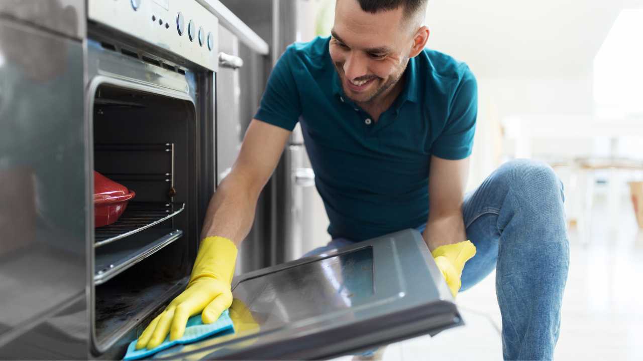 Uomo pulisce il vetro del forno