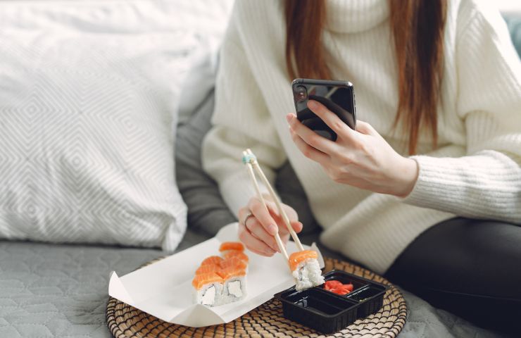 Ragazza con smartphone mentre mangia