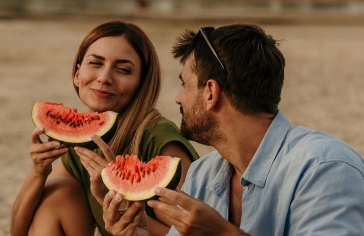 Due persone mangiano anguria in spiaggia