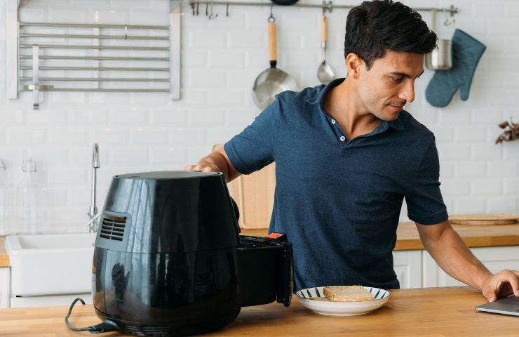 Uomo che usa la friggitrice ad aria