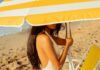 Donna in spiaggia sotto all'ombrellone