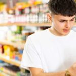 Un giovane che controlla della passata di pomodoro al supermercato