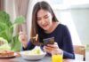 Ragazza che mangia consultando lo smartphone