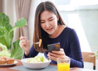 Ragazza che mangia consultando lo smartphone