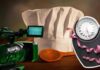 Un cappello da chef ed una telecamera televisiva con una bilancia ed un metro