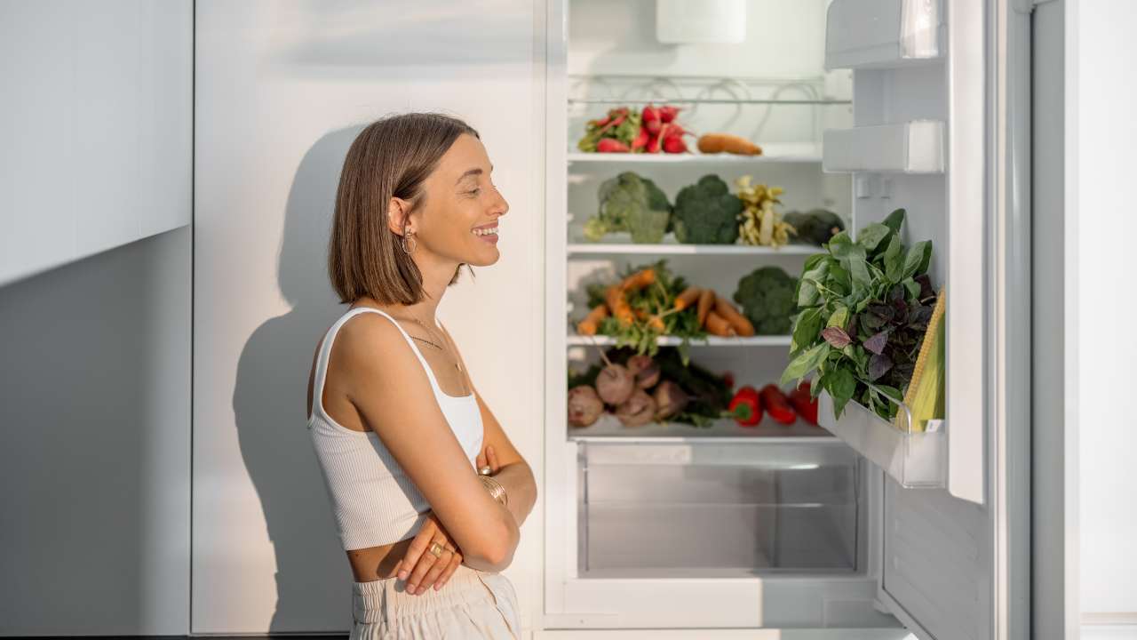 Una donna contenta davanti ad un frigorifero aperto