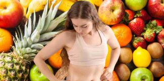 Una donna che tocca i suoi fianchi e della frutta come sfondo
