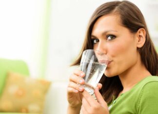 Una donna che beve acqua da un bicchiere