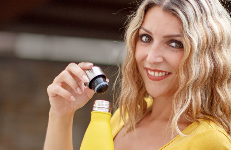Una donna che svita il tappo di una borraccia