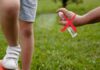 Un adulto spruzza dello spray antizanzare su un bambino