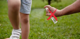 Un adulto spruzza dello spray antizanzare su un bambino