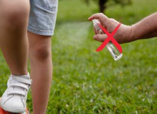 Un adulto spruzza dello spray antizanzare su un bambino