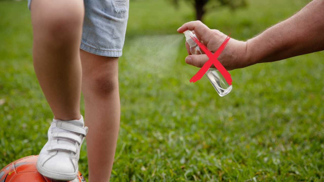 Un adulto spruzza dello spray antizanzare su un bambino